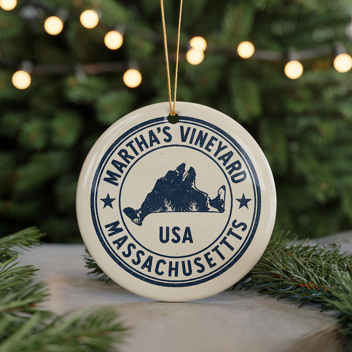 A white ornament with a blue border and text, featuring the name 'Martha's Vineyard, USA', is displayed on a Christmas tree branch.