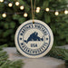 A white ornament with a blue border and text, featuring the name 'Martha's Vineyard, USA', is displayed on a Christmas tree branch.