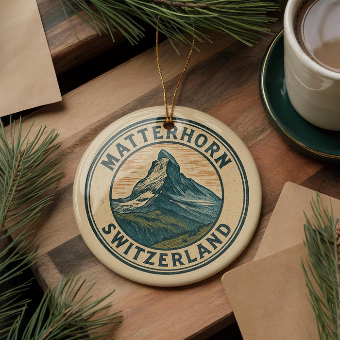 A circular ornament with the text "MATTERhorn SWITZERLAND" and a mountain illustration, placed on a wooden surface next to a cup of coffee and pine branches.