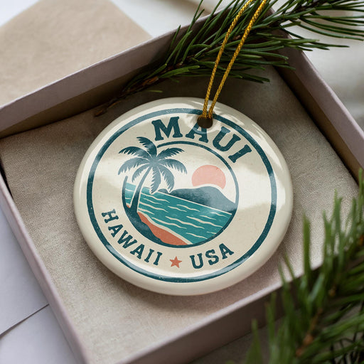 A circular ornament with the text "MAUI HAWAII USA" printed on it, surrounded by a palm tree and a sunset.