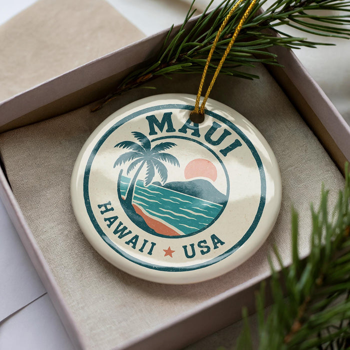 A circular ornament with the text "MAUI HAWAII USA" printed on it, surrounded by a palm tree and a sunset.