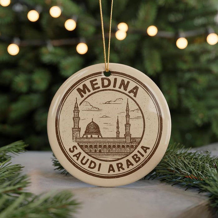 A circular ornament with the text "MEDINA SAUDI ARABIA" printed on it, featuring an illustration of a mosque and palm trees.
