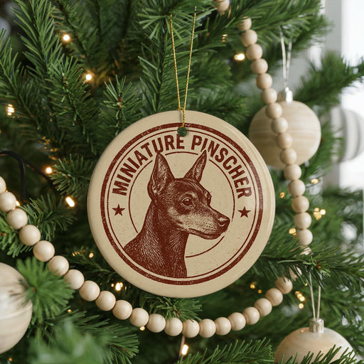 A Christmas tree decorated with ornaments, including a circular ornament with a dog's head and the text "MINIATURE PINSCHER" printed on it.