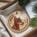 A round ornament with a dog's head and the text "MINIATURE PINSCHER" is displayed in a box, surrounded by pine branches.
