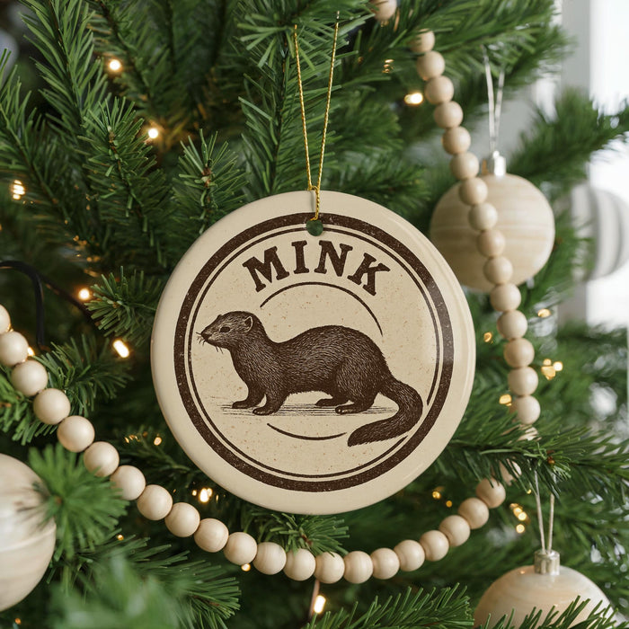 A Christmas tree decorated with ornaments, including a circular ornament with a picture of a brown animal and the word "MINK" written on it.