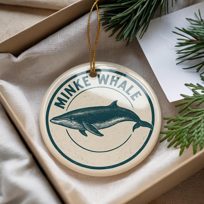 A round ornament with a blue and white design featuring a whale, hanging from a string.