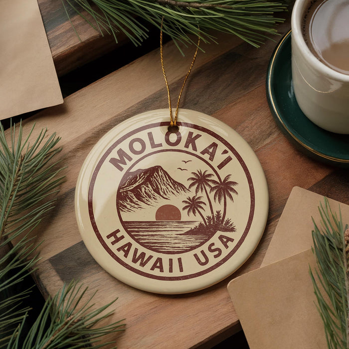 A circular ornament with the text "MOLOKA'I HAWAII USA" printed on it, surrounded by pine branches and a cup of coffee on a wooden surface.
