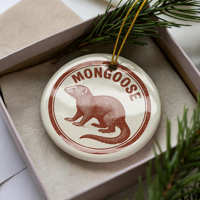 A round ornament with a brown and white design featuring a moose, placed inside a box with pine branches.