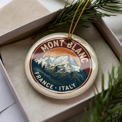 A decorative ornament in a box, featuring a mountain landscape with the text "MONT BLANC FRANCE ITALY" around the edge.