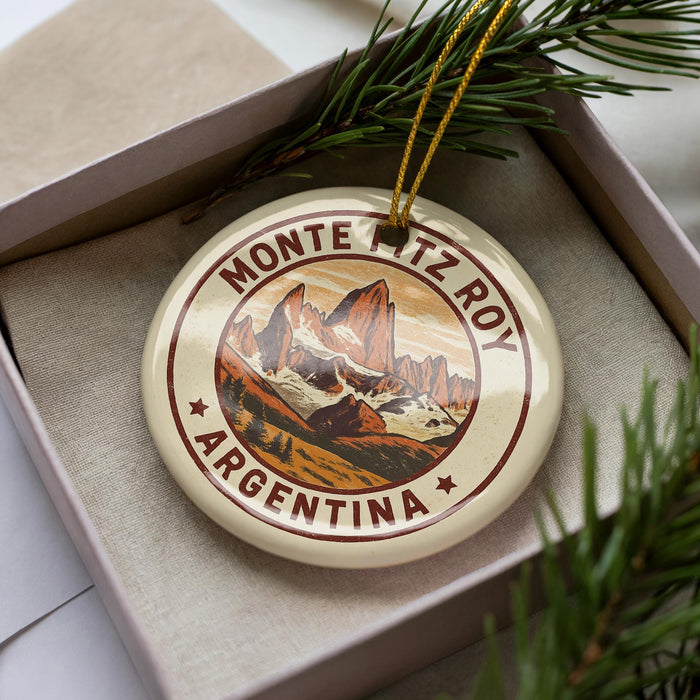 A decorative ornament in a box, featuring a mountain landscape with the text "MONTE PITZ ROY ARGENTINA" around the edge.