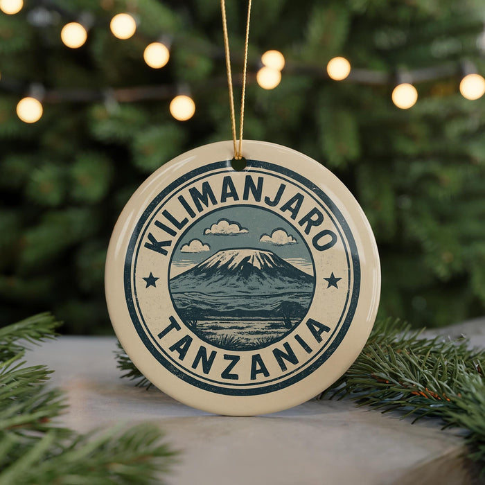 A circular ornament with the text "KILIMANJARO TANZANIA" printed on it, surrounded by a mountain and clouds.