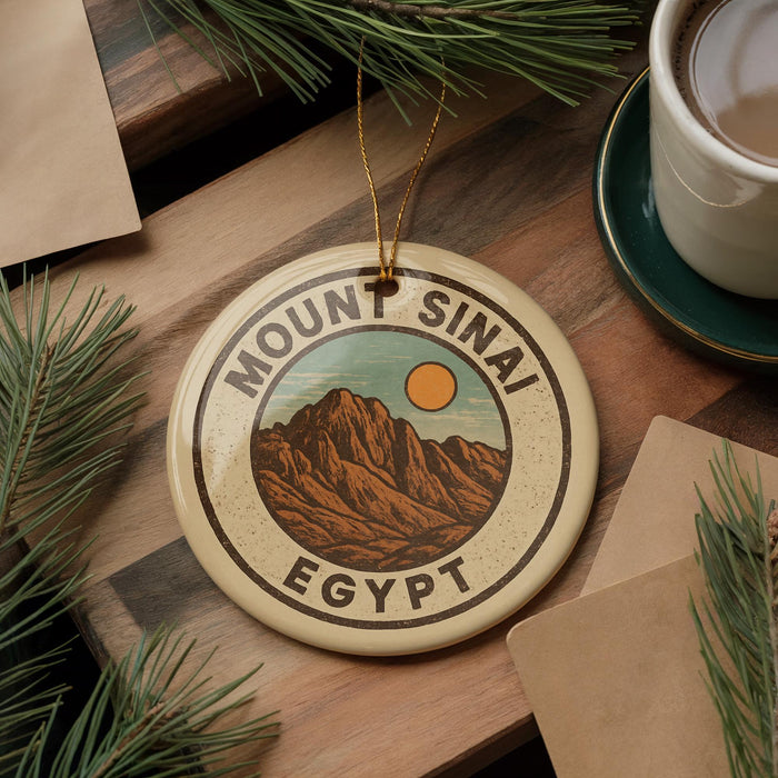 A circular ornament with the text "MOUNT SINAI EGYPT" and an illustration of a mountain range, hanging on a wooden surface.