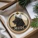 A circular ornament with a dog's head and the word "MUDI" printed on it, hanging from a string.