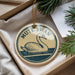 A round ornament with a swan image and the text "MUTE SWAN" is displayed in a box with pine branches.