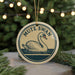 A round ornament featuring a swan swimming in a body of water, with the text "MUTE SWAN" displayed on it.