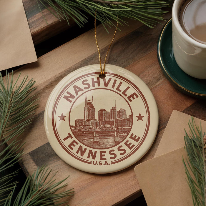 A circular ornament with the text "NASHVILLE TENNESSEE" and an illustration of a city skyline, hanging on a wooden surface.