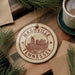 A circular ornament with the text "NASHVILLE TENNESSEE" and an illustration of a city skyline, hanging on a wooden surface.