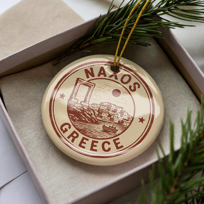 A circular ornament with the text "NAXOS GREECE" printed on it, surrounded by pine branches.