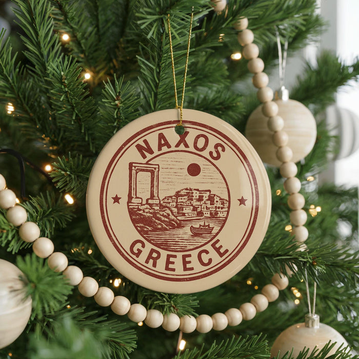 A Christmas tree decorated with ornaments, including a circular ornament with the text "NAXOS GREECE" and a small illustration of a Greek island.