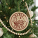 A Christmas tree decorated with ornaments, including a circular ornament with the text "NAXOS GREECE" and a small illustration of a Greek island.