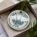 A circular ornament with the text "NEW YORK CITY USA" printed on it, featuring an illustration of the Statue of Liberty and the New York City skyline.