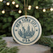 A circular ornament with the text "NEW YORK CITY USA" and an illustration of the Statue of Liberty in the center, hanging from a string.