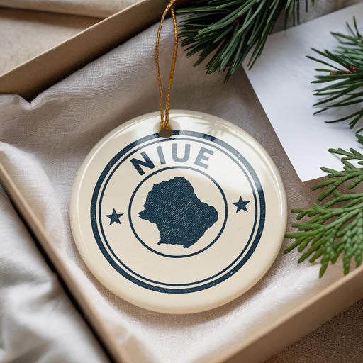 A decorative ornament with the word "NIUE" on it, surrounded by pine branches and a white paper.