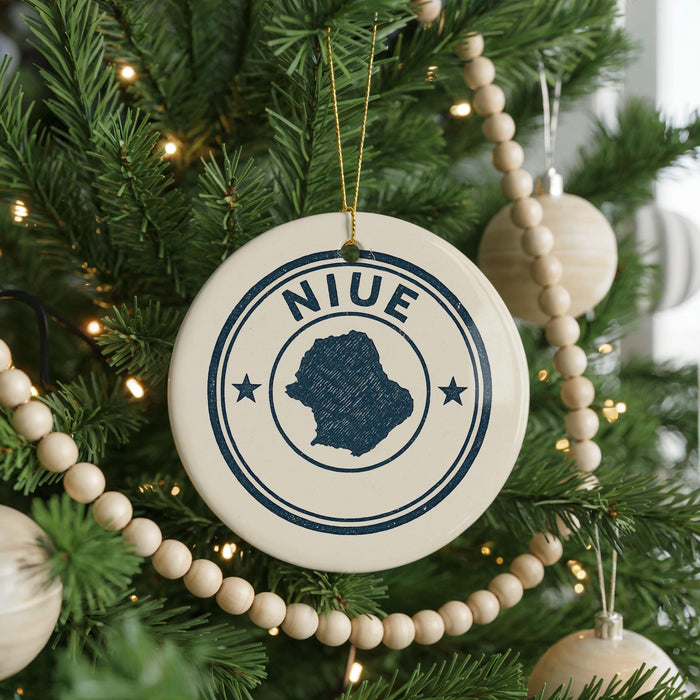 A Christmas tree decorated with ornaments, including a circular ornament with the word "NIUE" and a silhouette of a map of Niue.
