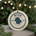 A white ceramic ornament with the word "NIUE" and a graphic of a map is displayed on a table, surrounded by pine branches and twinkling lights.