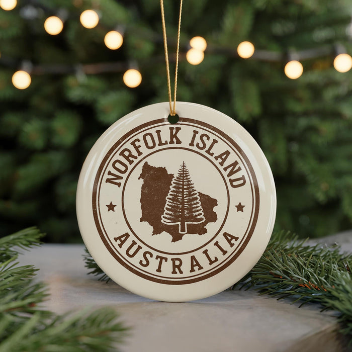 A white ornament with the text "NORFOLK ISLAND AUSTRALIA" printed on it, featuring a tree silhouette and a map of Norfolk Island.