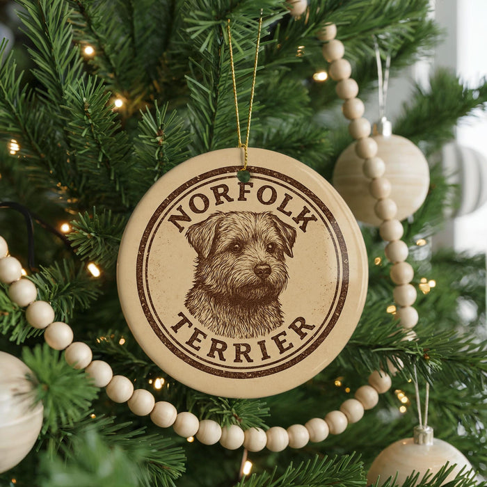 A round ornament on a Christmas tree featuring a terrier dog's head and the text "NORFOLK TERRIER".