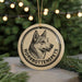 A round ornament featuring a black and white illustration of a dog's head, with the text "NORROBOTTENSPEATS" around the edge.