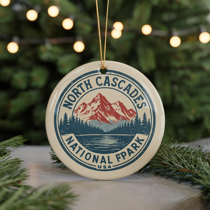 A round ornament with a mountain and pine tree design, featuring the text "NORTH CASCADES NATIONAL FPRK" and "U.S.A."