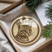 A round ornament with a cat's face on it, hanging from a string.