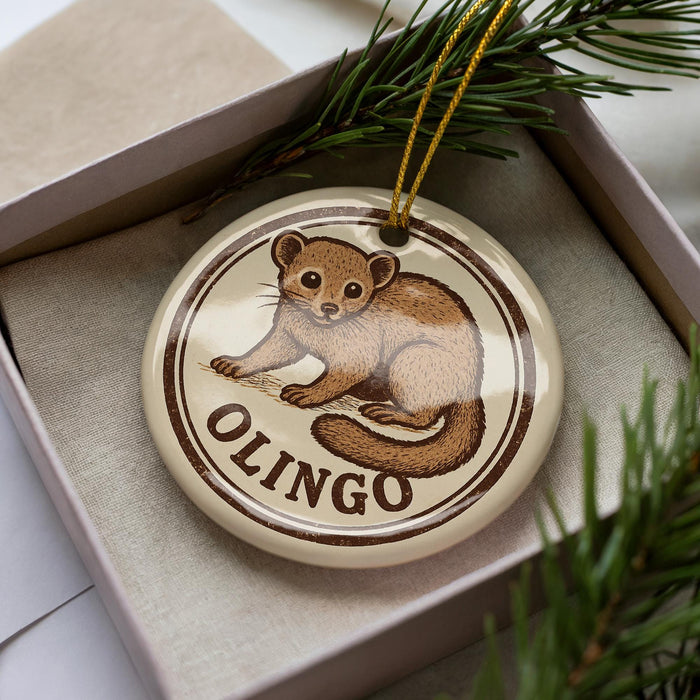 A round ornament with a brown and white design depicting a brown animal, possibly a rodent or small mammal, sitting on a branch. The word "OLINGO" is written below the image.