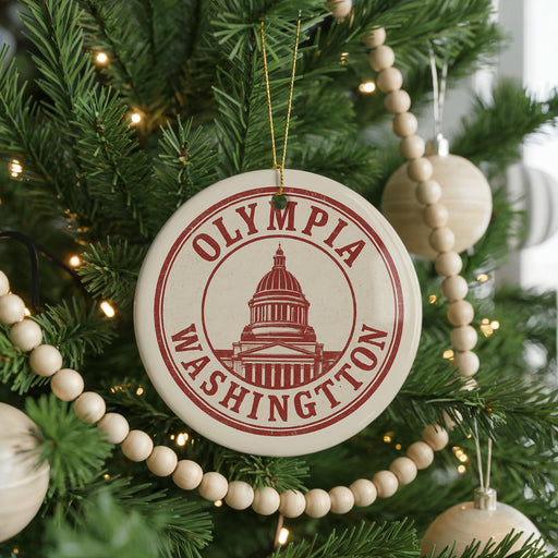 A Christmas tree decorated with ornaments, including a circular ornament with the text "OLYMPIA WASHINGTON" and a wooden bead decoration.