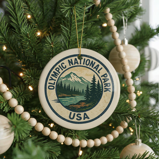 A Christmas tree decorated with ornaments, including a circular ornament with the text "Olympic National Park USA" and a mountain landscape.