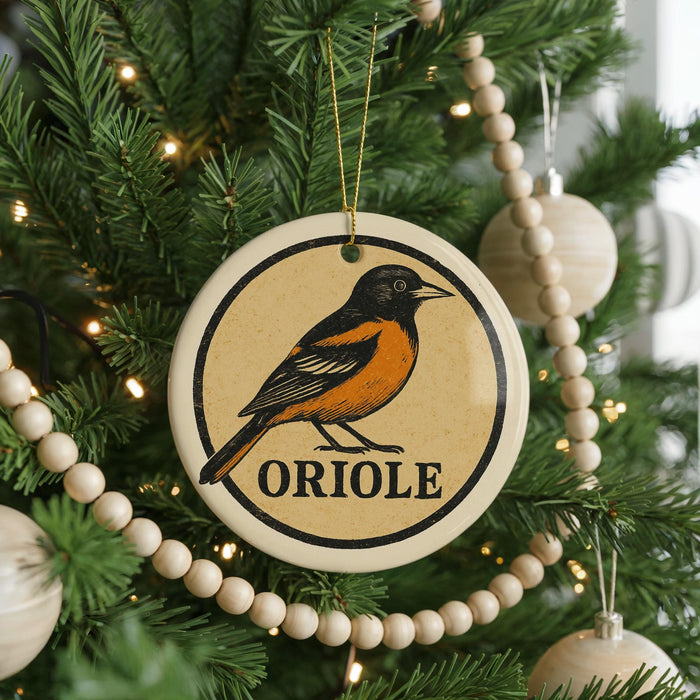 A Christmas tree decorated with ornaments, including a circular ornament with an illustration of an oriole bird and the word "ORIOLE" written on it.