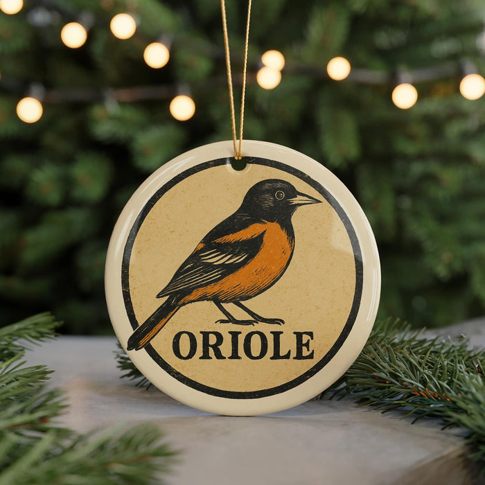 A ceramic ornament featuring an illustration of an oriole bird, with the word "ORIORE" written below it.