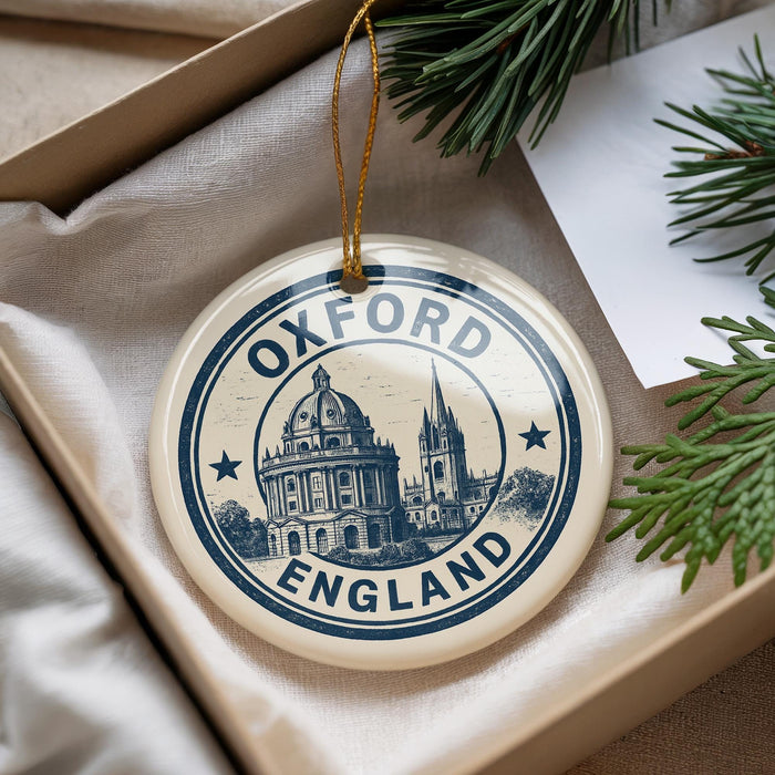 A decorative ornament with the text "Oxford England" and an illustration of a building, placed in a box with pine branches.