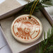 A circular ornament with the text "PATAS MONKEY" printed on it, featuring an illustration of a monkey's face.