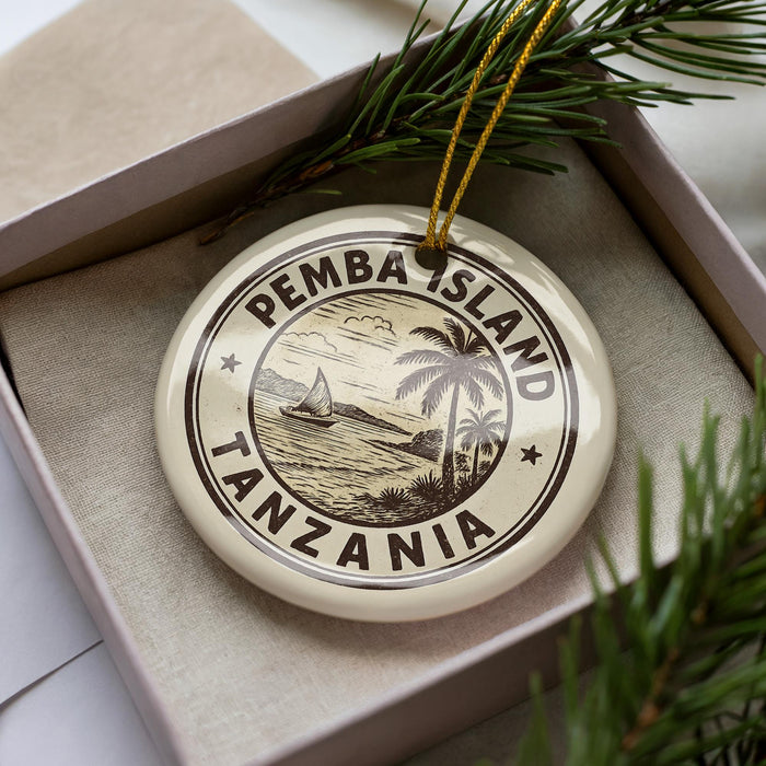 A decorative ornament in a box, featuring a circular design with the text "PEMBA ISLAND TANZANIA" and a depiction of a sailboat on the water.