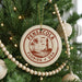 A round ornament on a Christmas tree, featuring a lighthouse and palm trees, with the text "Pensacola, Florida USA" printed on it.