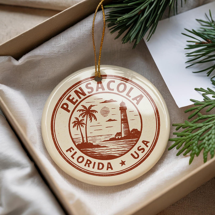 A round ornament with the text "PENSACOLA FLORIDA USA" printed on it, hanging from a string.