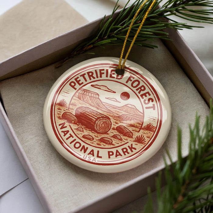 A circular ornament with the text "PETRIFIET FOREST NATIONAL PARK USA" printed on it, placed inside a box with pine branches.