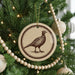 A Christmas tree decorated with ornaments, including a circular ornament featuring a bird design.