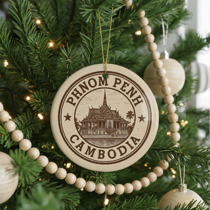 A Christmas tree decorated with ornaments, including a circular ornament with the text "PHNOM PENH CAMBODIA" and a temple illustration.