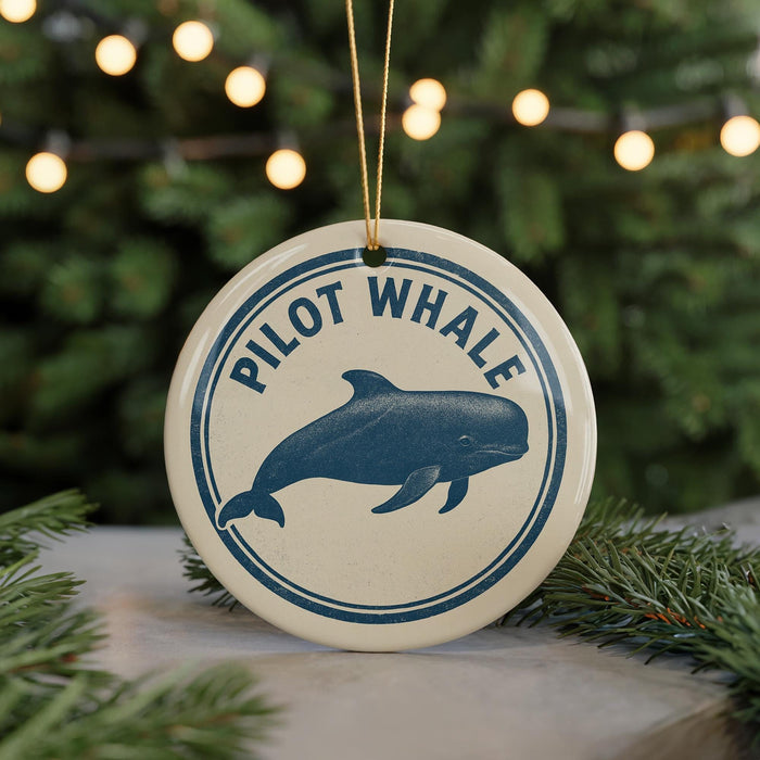 A round ornament with a blue and white design featuring a pilot whale, hanging from a string.