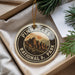 A circular ornament with the text "PINNACLES NATIONAL PARK" and an illustration of mountains, placed in a box with pine branches.