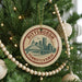 A round ornament on a Christmas tree, featuring a cityscape and the text "PITTSBURGH PENNSYLVANIA".